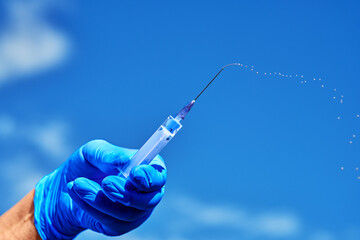 A syringe with medicine in his hands . A nurse with a dose of vaccine .