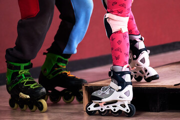 Two pairs of roller skates close-up in the rolling room. The coach teaches the child to...