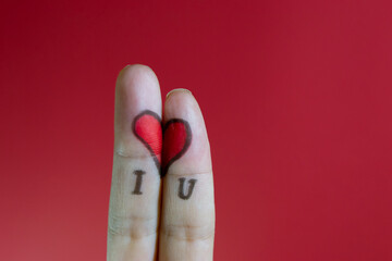 Painted heart on female fingers on red background. Inscription I Love You. Valentine day concept.