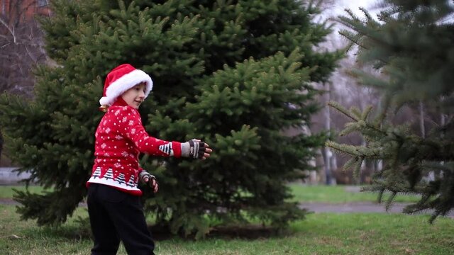 a boy in a Christmas red sweater with a reindeer and a Santa hat in the park makes a kick with a U-turn. High quality FullHD footage