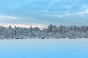 Winter snowy landscape with lake, trees, branches with show, ice and cold weather