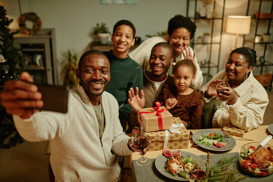 High angle portrait of happy African-American family taking selfie photo while enjoying Christmas at home together