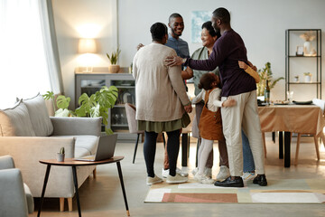 Full length portrait of big African-American family embracing while welcoming guests for dinner...