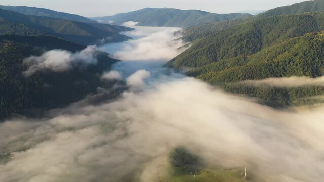 Aerial view on amazing flowing morning fog spreads over green meadows in autumn mountains. Ukrainian Carpathian mountains. UHD 4k video