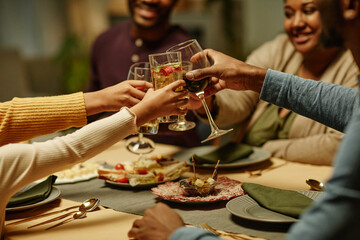 Side view close up of African-American family clinking glasses while enjoying dinner party at home, copy space
