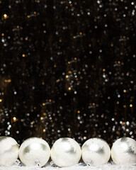Christmas banner decorations view of five silver evening balls with white snow on it on dark background with silver colors bokeh and artificial snow. Holidays concept with copy space