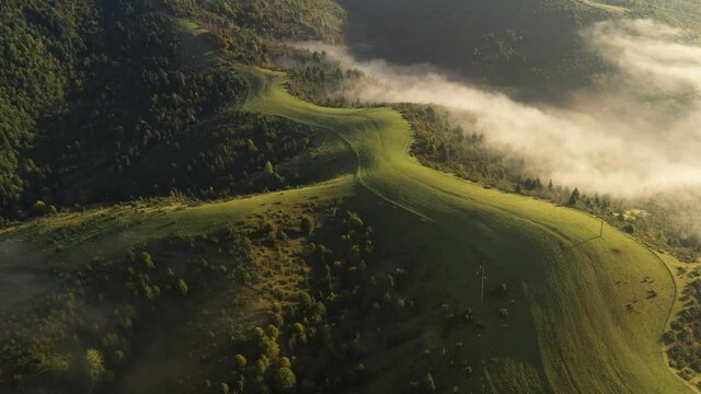Aerial view on amazing flowing morning fog spreads over green meadows in autumn mountains. Ukrainian Carpathian mountains. UHD 4k video