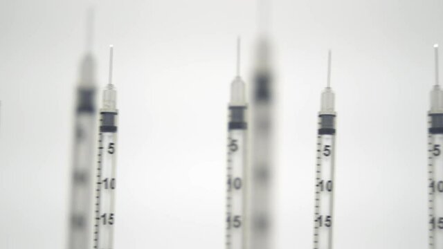 Empty vaccine syringes and medical needles standing upright on a table pan slide dolly