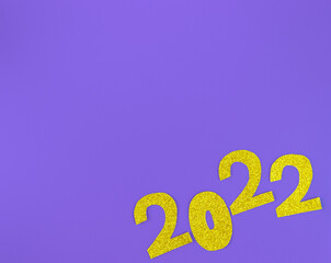 golden glittering shapes of numbers 2022 on purple background with round coffeetti, minimalism new year concept. Place for text