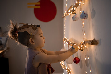 Toddler girl decorating christmas tree at home. Eco friendly alternative Christmas tree