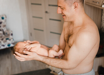 Happy and proud father holding his newborn son on his arm. Newborn baby on father's arms. Selective focus. Film grain