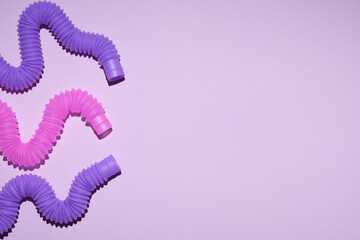 Multi-colored corrugated plastic pipes on a bright background. Popular poptube game on a lilac background