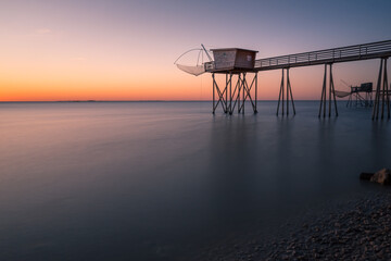 Typical old wooden fishing huts on stilts called « carrelet » in the atlantic ocean near La Rochelle, France. shot taken at sunset.