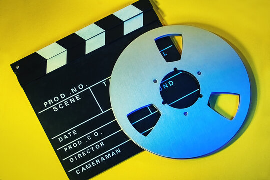 Movies concept photo with a film board and a tape spool in a yellow background. A cinema template
