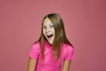 Happy positive exited cute little girl child with open mouth, grimacing, screaming wow on pink...