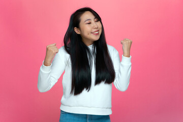 Overjoyed young asian girl feel euphoric, excited pleased with win, personal success on pink studio...