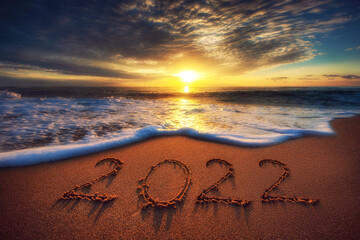 Happy New Year 2022 concept, lettering on the beach. Sea sunrise