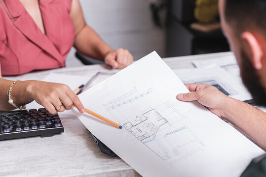 Personas desconocidas analizando y arreglando planos de construcci&oacute;n en una oficina de arquitectura