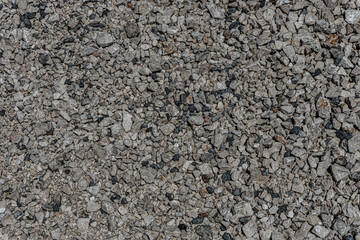 The texture of fine gravel. Granite gray back. Lots of small stones lying on the ground.