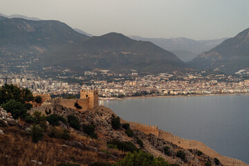 Alanya, Turkey - 16 July 2021. The historical Red Tower , castle wall and ruins of historical harbor of Alanya