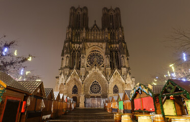 Cathedral of Notre Dame, Reims and Christmas market stalls in the night. One of the most stunning masterpieces of 13th century Gothic art. - obrazy, fototapety, plakaty