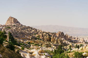 Naklejka premium Cappadocia, Turkey - 20 July 2021. Day view of Goreme town with blue clear sky on horison. Famous center of balloon fligths