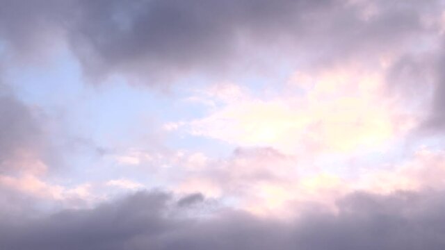 View of white and pink clouds parading in a blue sky.  Cloudy frame for background.