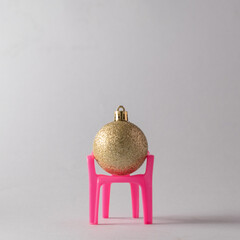 Golden Christmas ball in a pink chair. New Year's concept.Copy space