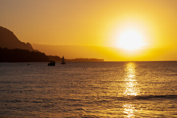 Naklejka na ściany i meble Dramatic orange sunset with sailboat from the Hanalei Pier in Kauai