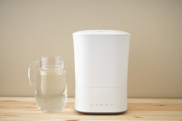 Ultrasonic humidifier and water decanter on a wooden table.