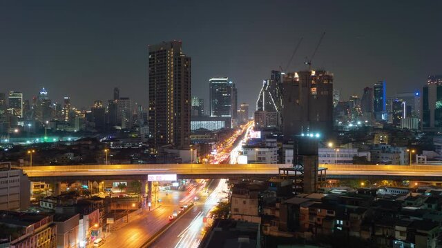 Time lapse of aerial view of intersection or junction with cars traffic, Bangkok Downtown. Thailand. Financial district in smart urban city and technology. Skyscraper office buildings at night