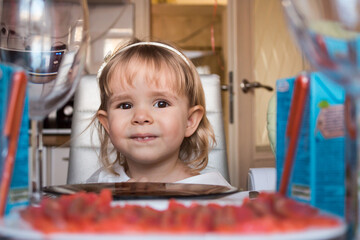 Little girl celebrates a birthday, head close on the background of a festive table