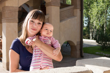 Mom hugs baby girl, sunny weather in the park, waist-deep view