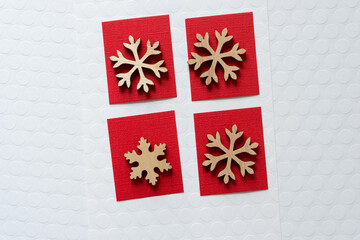 four wooden snowflake ornaments isolated on red paper squares