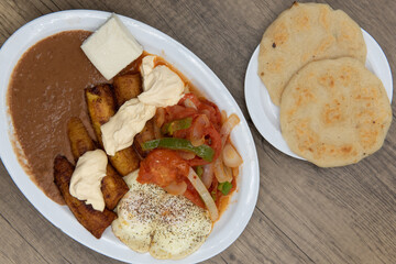 Overhead view of fried plantains on a plate with refried beans, stir fried vegetables, and eggs...
