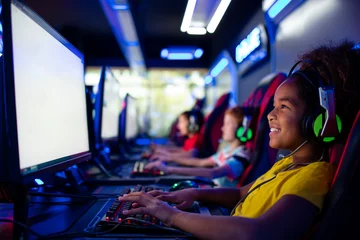 Fototapete Gaming Group of kids in game room sitting and playing computer video games - entertaining industry.  © littlewolf1989