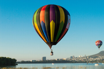 Fototapeta premium Globo aerostático volando sobre un lago