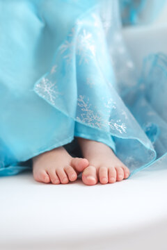Child toes peeking out of a long blue winter queen costume