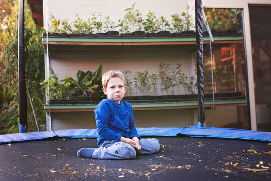 Young boy sitting on a trampoline and cry