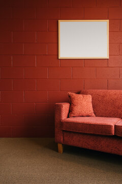 Fototapeta A red couch and pillow against a red brick wall