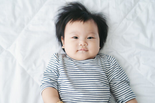 Cute baby lies in a white round bed.