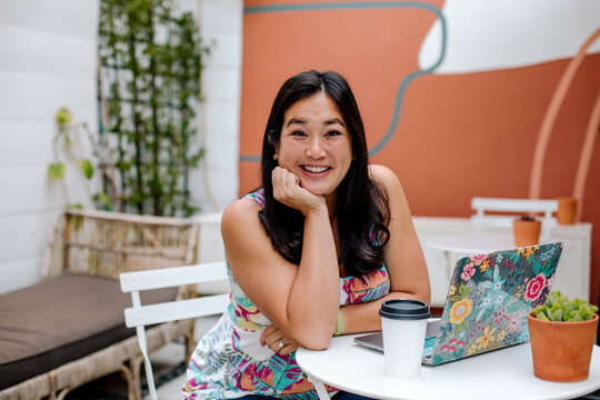 Smiling woman with laptop at outdoor cafe