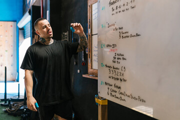 Hispanic trainer planning workout on whiteboard