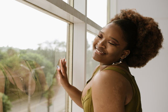 A smiling girl near the window in a fancy look