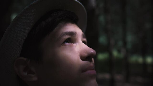 teen boy looking at the sky at the rising sun in the forest, connect with nature