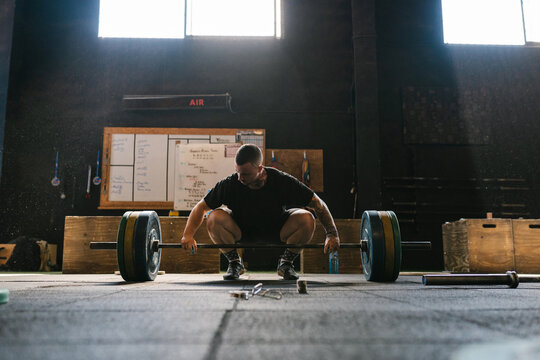Sportsman preparing to lift heavy barbell in gym