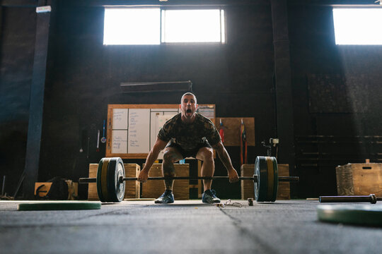 Athlete lifting a very heavy barbell with full strength