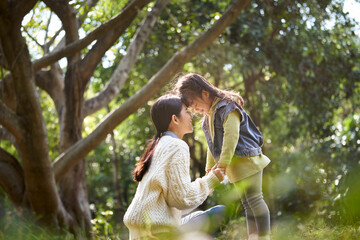 Naklejka premium asian mother and daughter having a good time outdoors in park