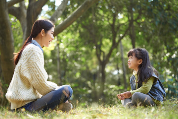 asian mother and daughter having a conversation outdoors in park