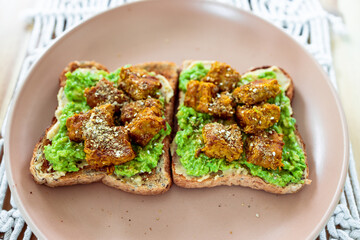 vegan avocado toast topped with marinated tempeh and dukkah, healthy plant-based food